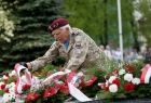 Wojkowy weteran w mundurze z czerwonym beretem układa kwiaty na płycie Grobu Nieznanego Żołnierza