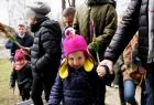 Uśmiechnięte dziecko z wielkanocną palemką prowadzone za rękę przez rodzica