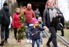 Rodzice z dziećmi wychodzący z palmami wielkanocnymi po nabożeństwie w drewnianym, zabytkowym kościele