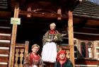 Iwona Gibas z zarządu województwa oraz panie w strojach ludowych przed drewnianą chatą w skansenie w Wygiełzowie