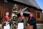 Iwona Gibas z Zarządu Województwa Małopolskiego oraz panie w strojach ludowych prezentujące palmę wielkanocną. Z tyłu zabytkowy drewniany kościół