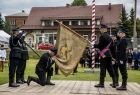 Strażak klęka przed sztandarem.