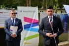 Przed mikrofonem stoi wicemarszałek Łukasz Smółka. Z tyłu baner z napisem Małopolska.