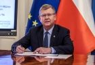 Marszałek Witold Kozłowski podpisuje umowę. Za nim widoczna flaga Polski i Unii Europejskiej.