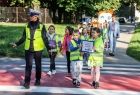 Policjantka przeprowadza dzieci przez przejście dla pieszych.