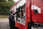 Wicemarszałek Łukasz Smółka ogląda wyposażenie nowego wozu strażackiego. Na boku widoczny napis Olszowice.