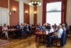 Sala, w której odbyło się spotkanie, widok z oddalenia, uczestnicy siedzą przy stole konferencyjnym