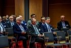 Samorządowcy siedzą na krzesłach.