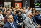 Widok na widownię sali konferencyjnej, widocznie ludzie.