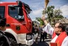 Ksiądz z kropidłem święci nowy wóz strażacki.