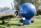 Balon z napisem małopolska stoi obok zabytkowego samolotu wojskowego.