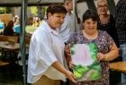 Europoseł Beata Szydło z kobietą trzyma w rękach pracę plastyczną.