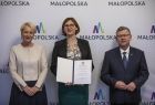 marszałek Witold Kozłowski i Iwona Gibas z zarządu z przedstawicielem Małopolskiej Rady Pożytku Publicznego, w tle ścianka z logo Małopolski