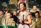 Prowadząca koncert, w tle orkiestra Straży Granicznej