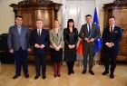 marszałek Witold Kozłowski, wicemarszałek Łukasz Smółka oraz kilka osób stoi na tle flag i pozuje do zdjęcia