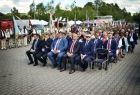 Goście uroczystości siedzą w rzędach na placu, słuchając przemówień