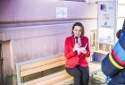 Kobieta siedzi na ławce przed budynkiem.