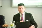 Wicemarszałek Łukasz Smółka siedzi przy stole. Przed nim laptop.