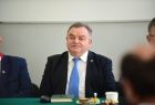 Mężczyzna w garniturze siedzi przy stole.
