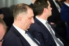 Mężczyźni w garniturach siedzą.