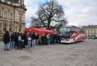 Rynek w Nowym Sączu, kolejka chętnych do oddania krwi ustawiła się do autokaru, w którym oddawana jest krew. Z lewej strony widać część budynku sądeckiego ratusza. Autokar jest w kolorze bieli i czerwieni znajduję się na środku rynku. 