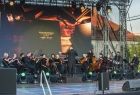 Koncert orkiestry, muzycy na scenie widoczni z oddalenia