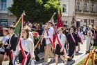 Młodzież ze szkoły w strojach galowych idzie w pochodzie.
