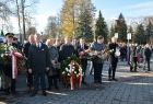 Grupa uczestników obchodów niepodległościowych z kwiatami i wieńcami