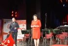 Radna Jadwiga Wójtowicz w trakcie przemowy na scenie. W tle widać logo Polskiego Czerwonego Krzyża. 