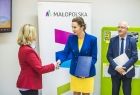 Marta Malec-Lech z zarządu województwa stoi podczas uroczystości przekazania umowy wraz z pozostałymi uczestnikami.
