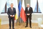 Marszałek Małopolski Witold Kozłowski w agendzie zamiejscowej UMWM w Nowym Sączu obok wójt gminy Łącko Jan Dziedzina. Mężczyźni stoją na tle okien i flag Polski, Unii Europejskiej i Małopolski. 