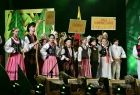 Dzieci i młodzież w kolorowych strojach regionalnych stoją na scenie w grupkach