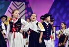 Dziewczynki w kolorowych sukienkach śpiewają na scenie