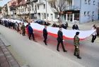 Uczestnicy obchodów niosą wspólnie flagę ulicami Krzeszowic