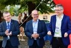 Marszałek Witold Kozłowski, burmistrz Starego Sącza Jacek Lelek i jedne z organizatorów Memoriału Jana Magiery, stoją na tle drzew i czerwonego balona. Mężczyźni są uśmiechnięci i bija brawo. 