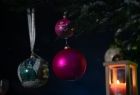 Widok na kolorowe ozdoby świątecznej w tym bombki, zawieszone na gałęziach choinki. 