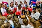 Wnętrze pomieszczenia, cheerleaderek stoją wokół okrągłego złotego tortu, jedna z dziewcząt, kroi tort, wokół nich zgromadziła się grupa młodszych dzieci. W tle widać 2 rolapy z logiem Małopolski i napis Małopolska. 