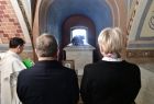 Marszałek Witold Kozłowski i wicemarszałek Iwona Gibas tyłem do zdjęcia stoją na przeciwko grobowca Jana Długosza. Marmurowy grobowiec spoczywa w łukowatej wnęce w kolorze niebieskim. Na ścianach widać mozaikę.