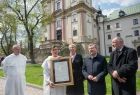 Dziedziniec Zakonu Paulinów na krakowskiej Skałce, W tle widać front budynku. Na zdjęciu od lewej strony widać trzech zakonników w białych habitach, wicemarszałek Iwona Gibas, marszałek Witold Kozłowski, prof. Jan Tadeusz Duda.