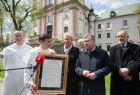  Dziedziniec zakonu Paulinów na krakowskiej Skałce, w tle widać mury zakonne. Na pierwszym planie, marszałek Witold kozłowski, prof. Jan Tadeusz Duda i wicemarszałek Iwona Gibas, przekazują zakonnika, pamiątkowy list intencyjny. 