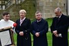  Dziedziniec zakonu Paulinów na krakowskiej Skałce, w tle widać mury zakonne. Na pierwszym planie, marszałek Witold kozłowski, prof. Jan Tadeusz Duda i wicemarszałek Iwona Gibas, przekazują zakonnika, pamiątkowy list intencyjny. 