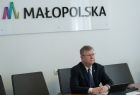 Marszałek Witold Kozłowski podczas spotkania online z szefem administracji Obwodu Lwowskiego Maksym Kozicki. Marszałek Witold Kozłowski siedzi przy biurku, na ścianę widać napis Małopolska i logo w Kształcie litery M.