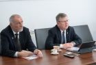 Marszałek Witold Kozłowski i Jan Tadeusz Duda podczas spotkania online z szefem administracji Obwodu Lwowskiego Maksym Kozicki. Mężczyźni siedzą przy biurku w ciemnobrązowych kolorach. W tle widać biała ścianę, samorządowcy spoglądają na wprost.