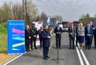 Uczestnicy wydarzenia, widoczna droga, zieleń i niebieski baner z napisem Małopolska.