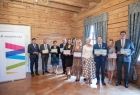 Grupa osób trzyma czeki, w tle ścianka z logo Małopolski