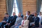 Goście wydarzenia siedzą na krzesłach, w tle widok na salę