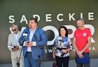 Parlamentarzyści (3 osoby) podczas wystąpienia; w tle napis "Sądeckie WOPR"
