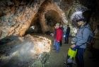 Widok na wnętrze jaskini i dwoje grotołazów, oświetlających wnętrze jaskini. 