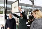 Mężczyzna unosi w górę w geście triumfu, Medal Polonia Minor. Po jego prawej stronie stoi Marszałek Witold Kozłowski po lewej radna Marta Mordarska. 