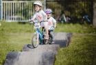 Dwoje małych dzieci jedzie na rowerkach po pofałdowanym torze rowerowym